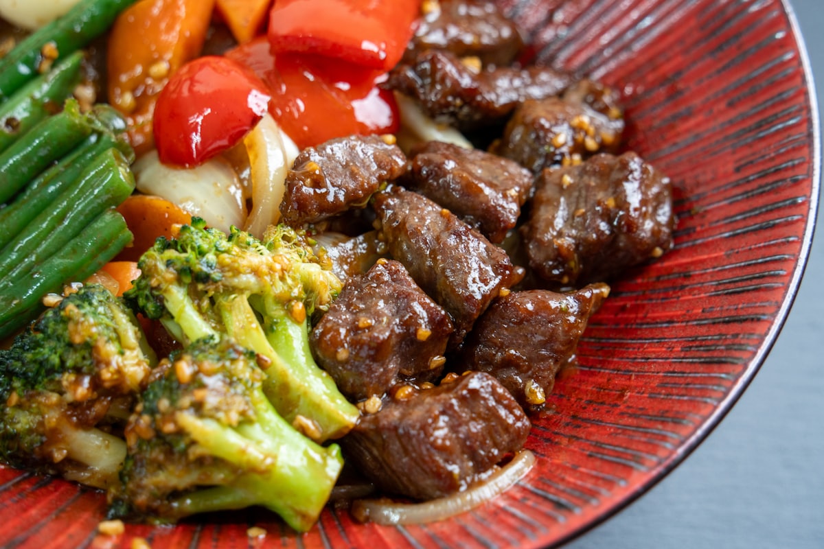 Stock photo of beef and vegetable stir-fry on a red plate — placeholder, not their kitchen