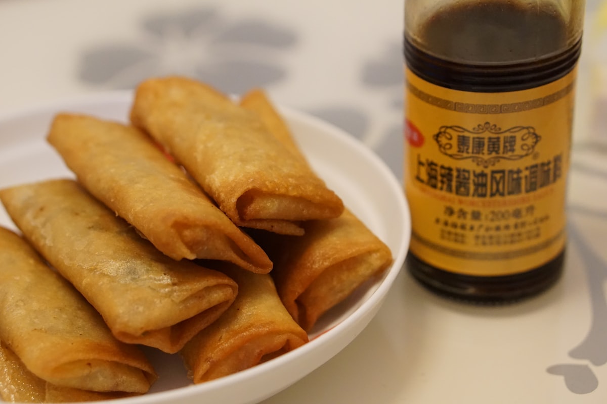 Stock photo of golden deep-fried Chinese egg rolls stacked on a plate — placeholder, not their kitchen